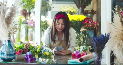 Attractive young store owner wearing apron, working in flower shop. Beautiful Stock Footage 138692853