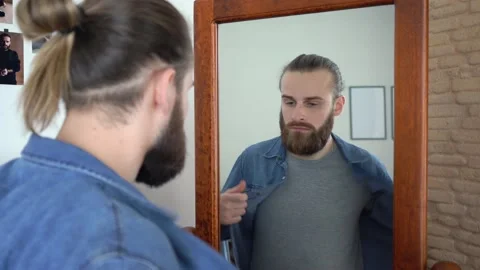 Attractive Young Stylish man is Combing His Beard Taking off his shirt Stock Footage 147894452
