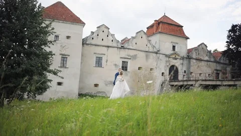 Attractive young wedding couple bride and groom walking before old castle on Stock Footage 95941360