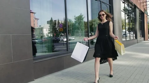 Attractive young woman pleased with her purchases walking outdoors Stock Footage