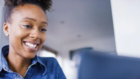 Attractive young woman smiling as she reads on her laptop Stock Photos
