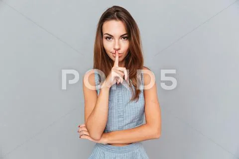 Attractive young woman standing and showing silence sign Stock Photos