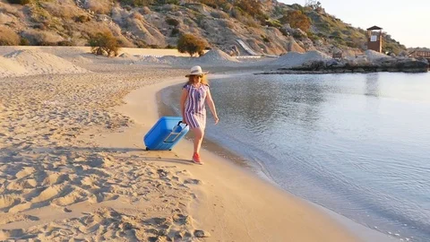 Attractive young woman with suitcase on the beach Stock Footage