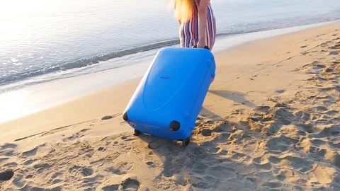 Attractive young woman with suitcase on the beach Stock Footage