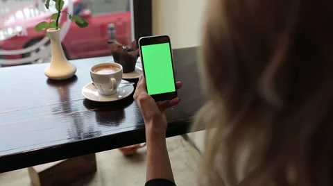Attractive young woman using her green touch screen mobile cell phone in cafe Stock Footage