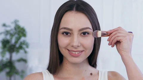 Attractive young woman using make up brush to applying make up. Stock Footage 106210587