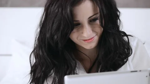 Attractive young woman using tablet computer touchscreen in her bedroom. Stockbeeldmateriaal 199628817