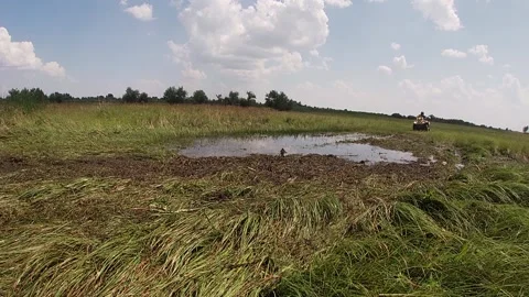 ATV bright drives through a puddle in a meadow Stock Footage 159353659