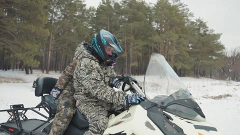 Atv riders examine engine readiness. Camoclad riders check snowmobile before Stock Footage 332170873