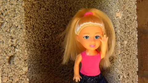Audacious Doll Waves From a Cement Block Stock Footage 105203130