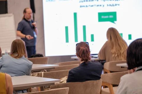 Audience at a business presentation with visual data on a projector screen Stock Photos