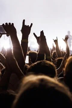 Audience hands raised in rock gestures at live music event Stock Photos