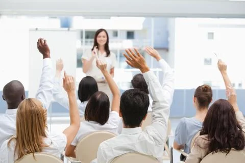 Audience raising their hands while watching a businesswoman 写真素材