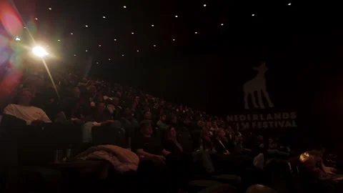 Audience seated inside cinema hall with Nederlands Film Festival logo Utrecht Stock Footage 318071302