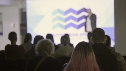 Audience silhouettes facing a brightly lit presentation stage Stock Footage 346761851