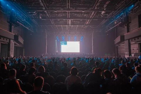 Audience sitting in front of stage with screen Stock Photos