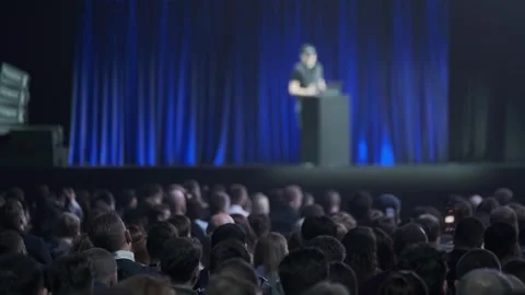 Audience watching speaker on stage during business conference presentation with Stock Footage 336332483