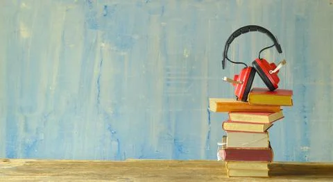 Audio book concept with stack of books and vintage headphones on blue grung.. Stock Photos