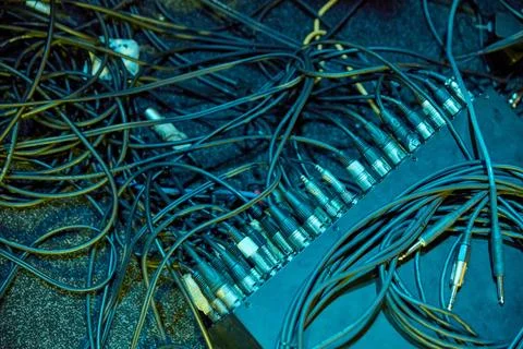 Audio cables connect mixing console across studio floor under teal light Stock Photos