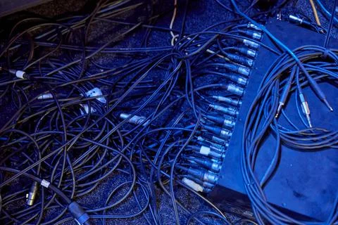Audio cables connect through stage gear under deep blue lighting Stock Photos
