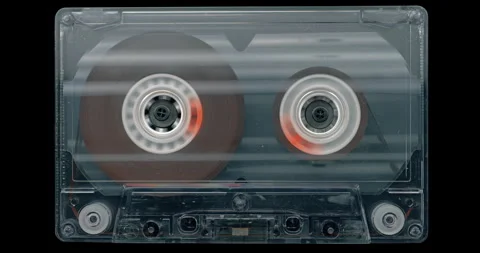 Audio cassette reels spin inside a transparent shell during analog playback 스톡 동영상 344996776