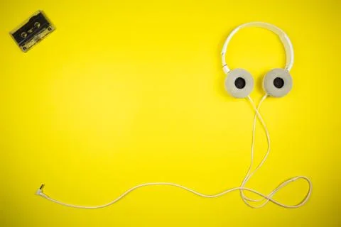 Audio cassette tape and modern headphones on a yellow background Stockfoto's