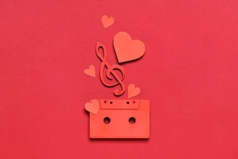 Audio cassette with treble clef and paper hearts on red background Stock Photos