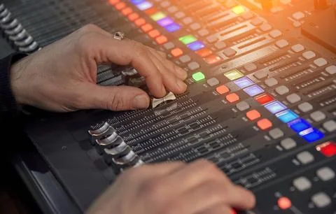 Audio engineer on audio mixer in studio adjusting volume levels. Broadcast, M Foto stock
