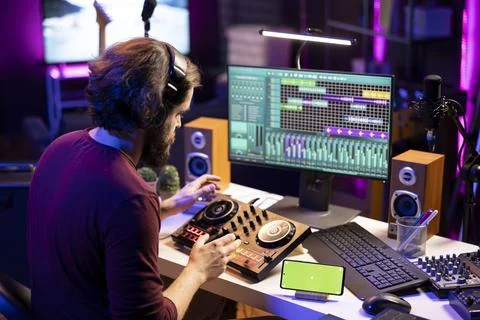 Audio engineer following online tutorial on smartphone greenscreen display 库存照片