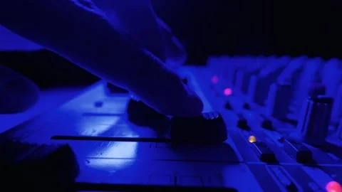 Audio Engineer Hand Adjusting Faders on Sound Mixing Console in Neon Light 動画素材 334737045