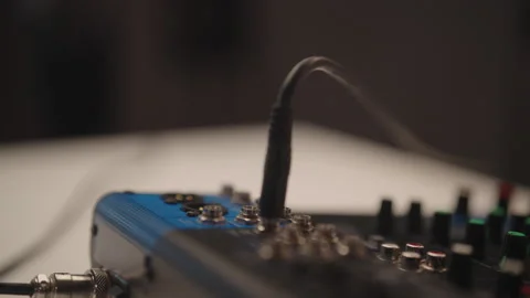 Audio engineer plugging multiple jack audio cables into input sockets of blue Stock Footage 323448611