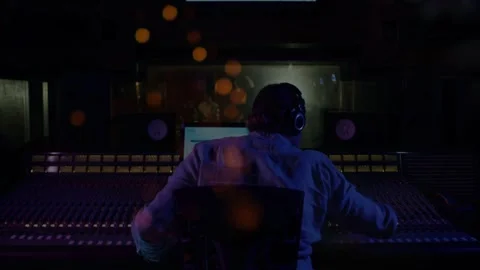 Audio engineer starting playback tweaking faders and balancing mix while orange Stock Footage 332523711