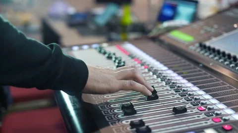 Audio engineer working on a professional console, moving faders, mixing music Stock Footage 76910744