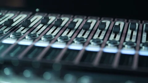 Audio mixer in a studio, the automatic knobs moving up on console. Close-up DOF Stock Footage 76927769