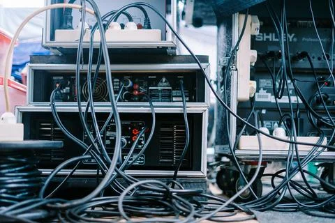 An audio mixer with various knobs, sliders, and connected cables Stock-Fotos