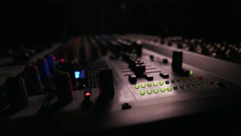 Audio Mixing Console Resting in Dark Studio with Glowing Green Lights Stock Footage 334736660