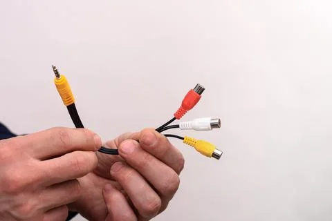 Audio video cable RCA jack in a man's hands on a white background. Stock Photos