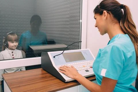 Audiologist doing hearing test to little patient 库存照片