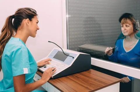Audiologist doing hearing test in special audio room 写真素材