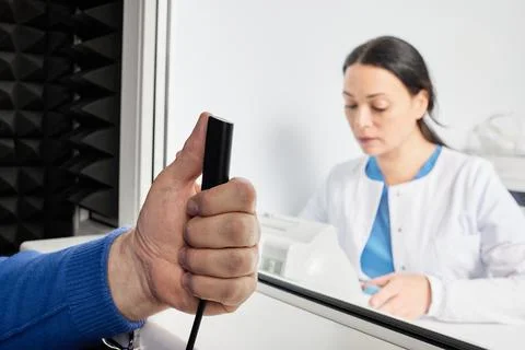 Audiometer patient response button in man's hand during audiometric testing.. Fotos Stock