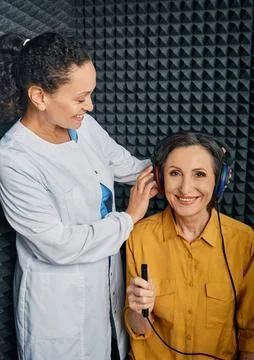 Audiometry exam. Audiologist doing hearing check-up to a mature woman in soun Foto stock