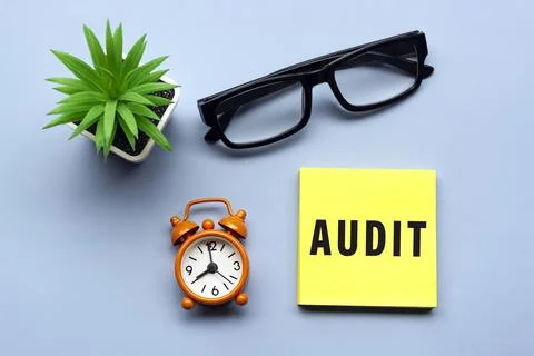 Audit text on adhesive Note with potted plant and alarm clock set at 8 o'clock. Stock Photos