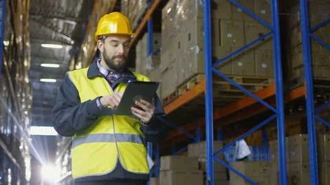 Auditor Wearing Hard Hat Uses Tablet Computer in Warehouse Full of Rack Pallets. Stock Footage 74371318