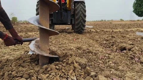 Auger Drill Bit Operating in Field with Tractor Background Stock Footage 334463147