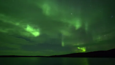 Aurora Borealis behind the clouds over the lake Stock Footage 250292181