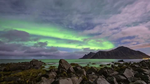 Aurora Borealis during cloudy night on rocky coast Stock Footage 250439206