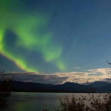 Aurora borealis moon-lit clouds over lake laberge Stock Photos