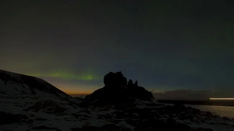 Aurora borealis moving over snow covered rocks at evening Stock Footage 73011034