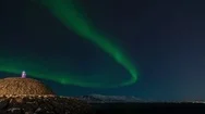 Aurora Borealis Over Lighthouse On Hill While Sea And Snowy Mountains Behind Stock Footage