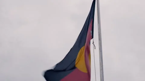Australian Aboriginal flag on flagpole on a windy, overcast day Stock Footage 272609911